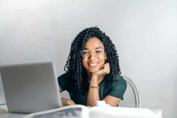 A black woman smiling in front of a laptop